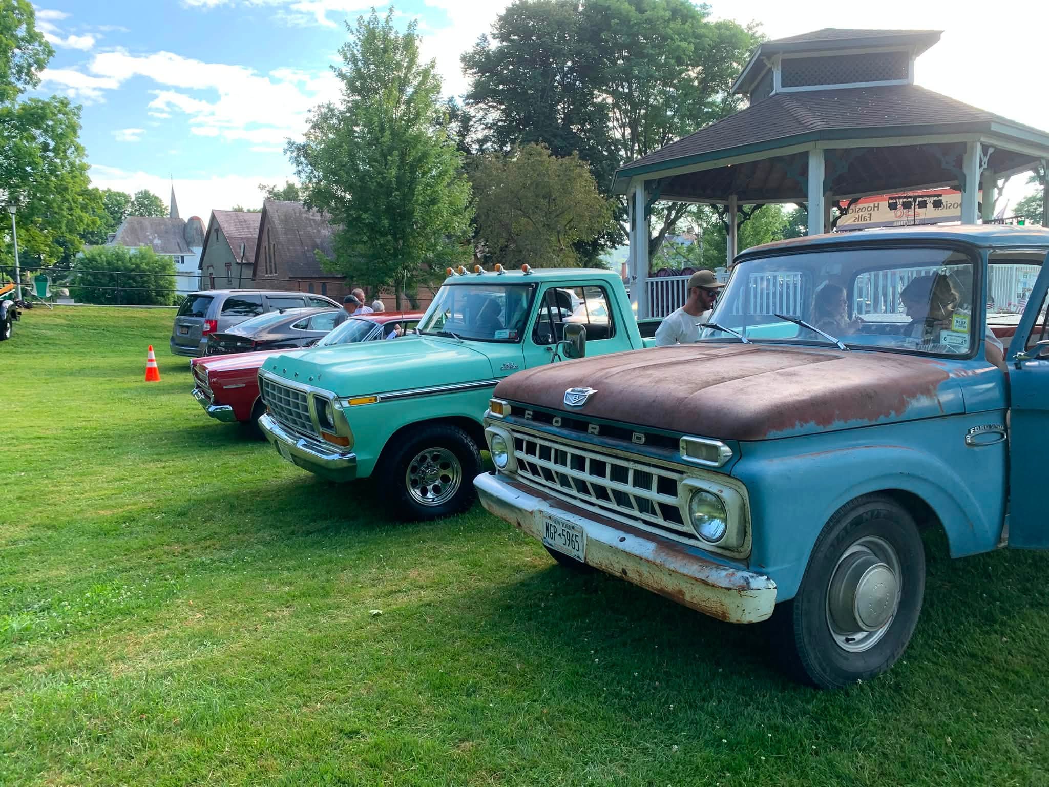 Vintage Ford pickups lined up nose to tail beside the Wood Park gazebo.