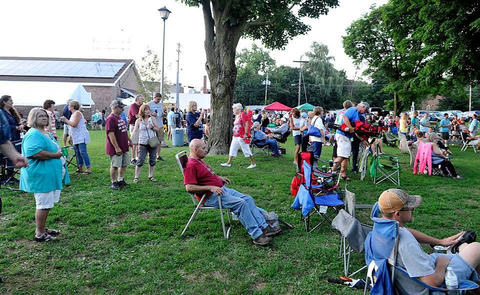 Neighbors spread across the Wood Park lawn with chairs and blankets at a concert.
