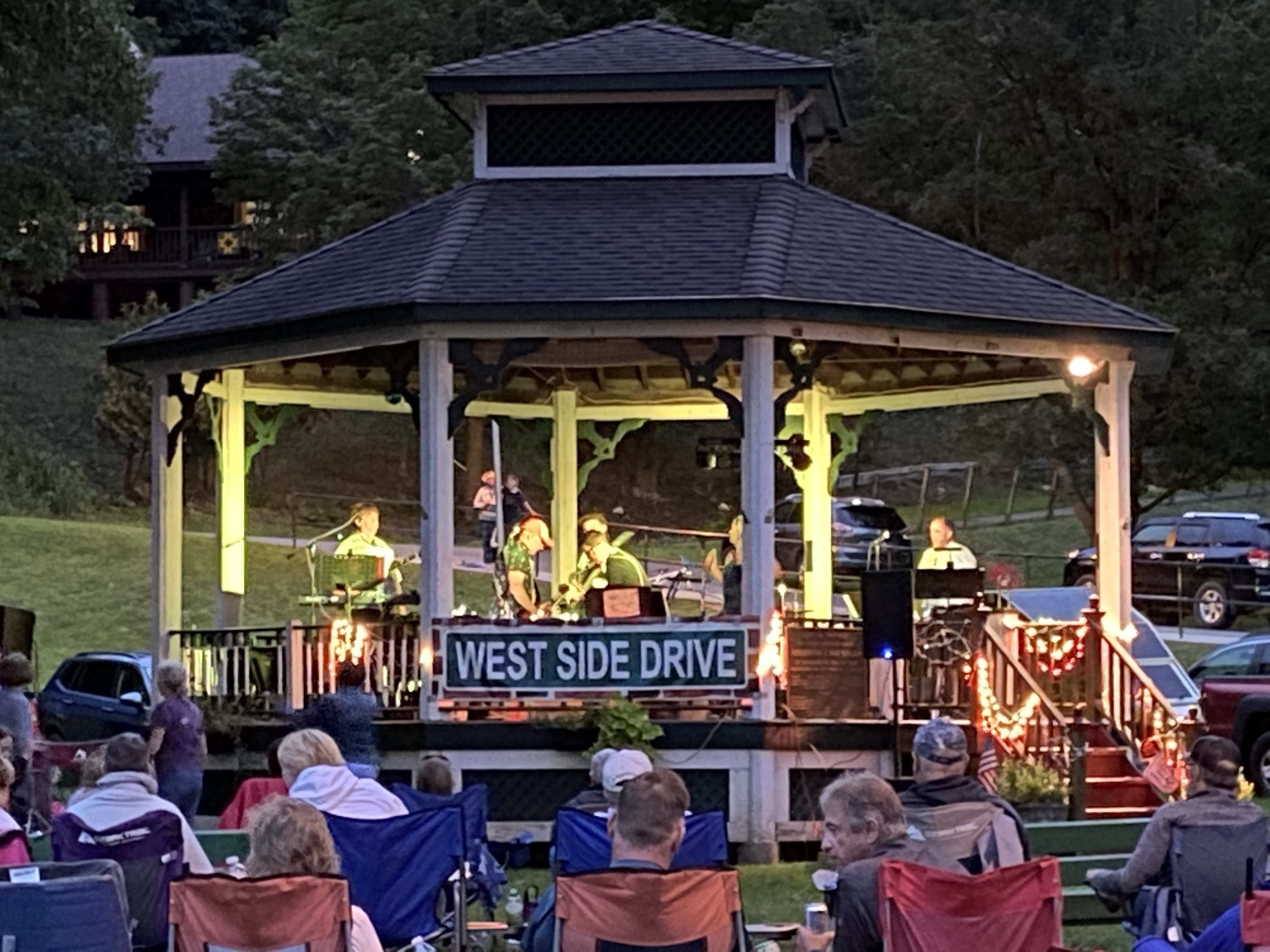 West Side Drive playing the Wood Park gazebo at dusk as neighbors watch from their lawn chairs.